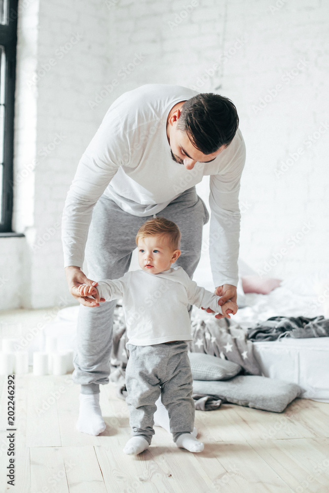 Young father playing and teaching his son doing first steps for a walk.. Young father playing and teaching his son doing first steps for a walk..