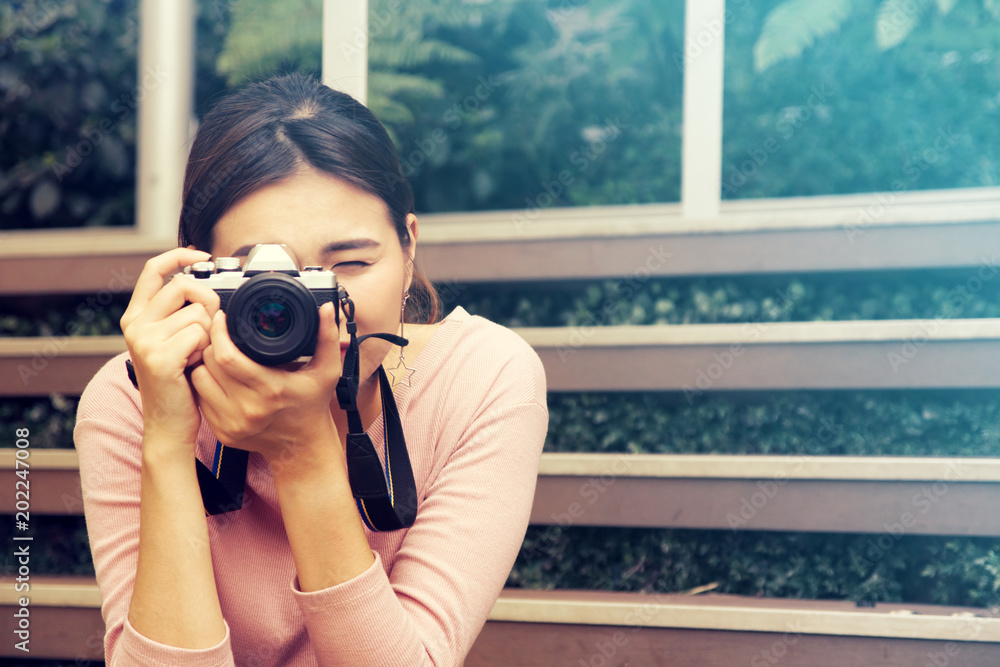 pretty cool young Asian woman with retro film camera or mirrorless camera in modern garden open mall. pretty cool young Asian woman with retro film camera or mirrorless camera in modern garden open mall.