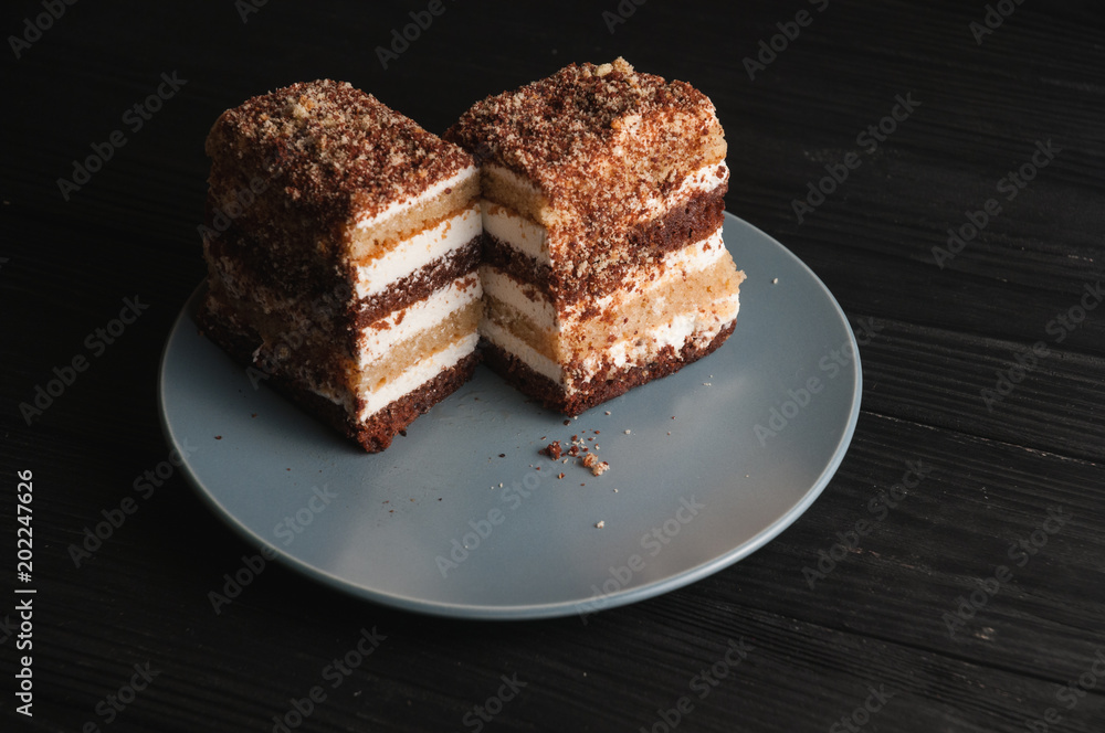 Traditional Italian dessert tiramisu on a gray plate on a black wooden background Traditional Italian dessert tiramisu on a gray plate on a black wooden background