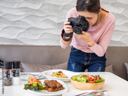 Women hold a camera in a hand and taking a picture for review in her blog.