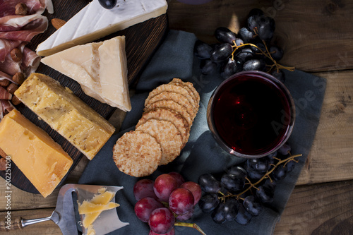 Different Dutch cheese, grapes and prosciutto, appetizers for a party and red wine.