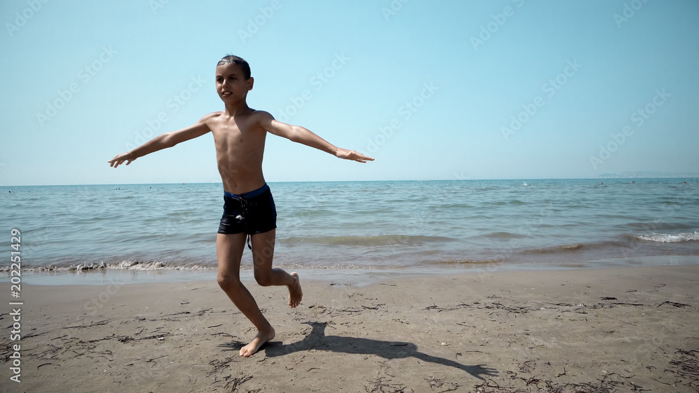 Happy boy getting out from the sea water. Front cinematic steadicam view Happy boy getting out from the sea water. Front cinematic steadicam view