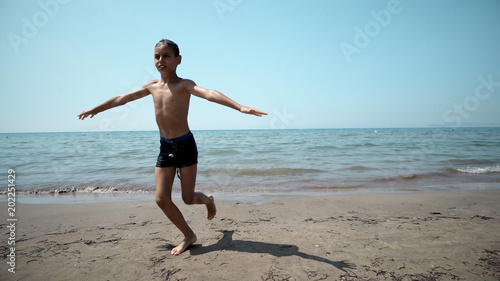 Happy boy getting out from the sea water. Front cinematic steadicam view