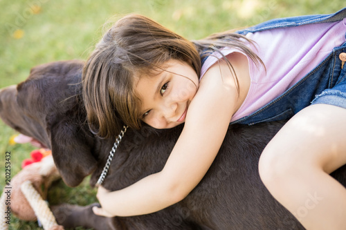 Innocent little girl hugging pet dog