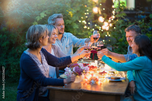 Photography One summer evening, friends in their forties gathered around a table in the garden lit by luminous garlands