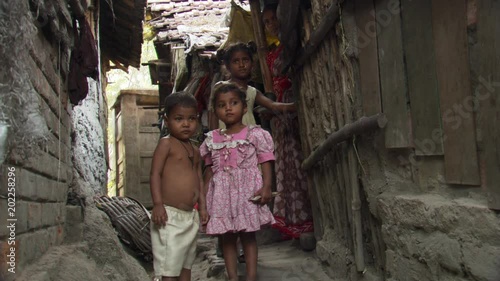 Children in Calcutta alley posing for portrait as mother looks on photo