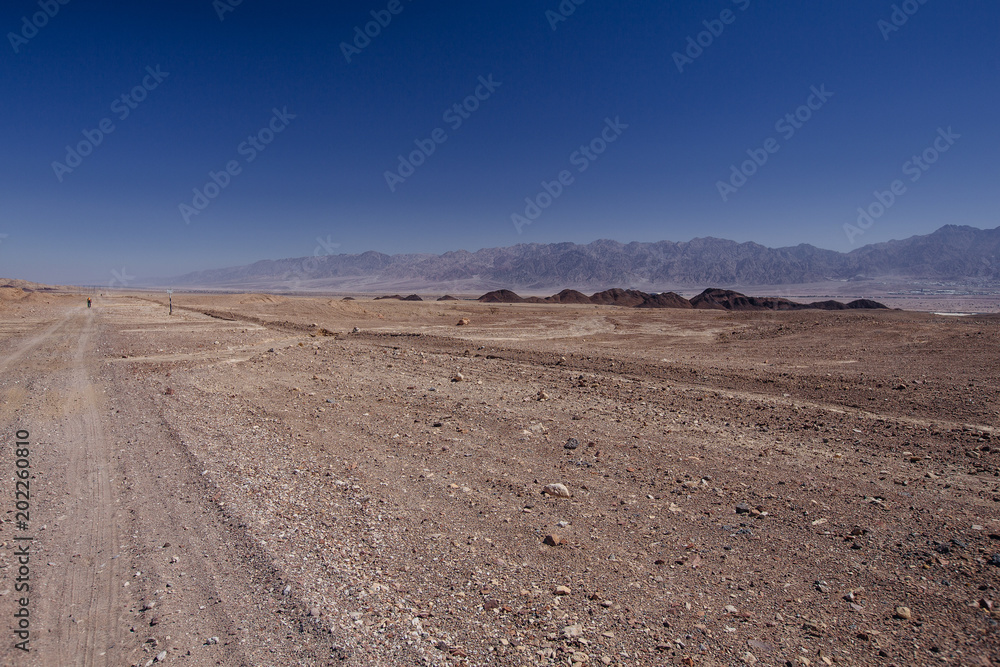 Way in the desert in the Israil in sunny day with red mountains and blue sky Way in the desert in the Israil in sunny day with red mountains and blue sky