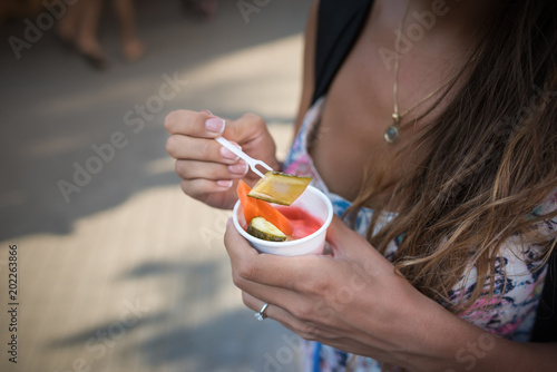 Canvas Print Close-up view of street local food in hands of young woman on blurred background