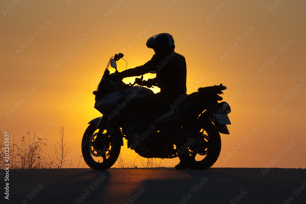 silhouette of rider on a motorbike admiring sunset - space for your text