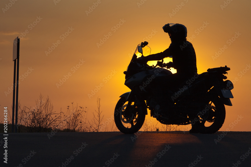 silhouette of rider on a motorbike admiring sunset - space for your text