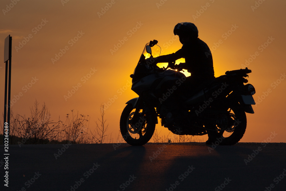 silhouette of rider on a motorbike admiring sunset - space for your text silhouette of rider on a motorbike admiring sunset - space for your text