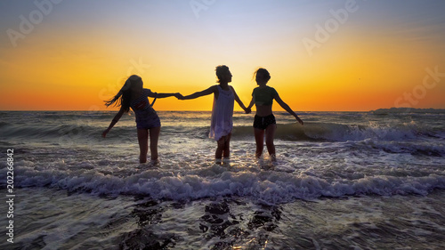 Group of female friends having fun splashing ocean waves on beach at sunset, cinematic steadicam SLOW MOTION © zefart