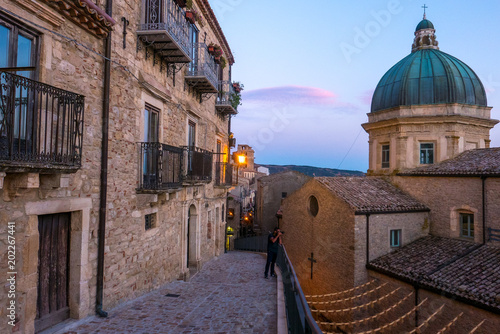 Tiny old village of Gangi, in Sicily, at sunset, with houses made of stone bricks, is a tipical example of sicilian farmer’s village. The church on the right has a blue metal dome.