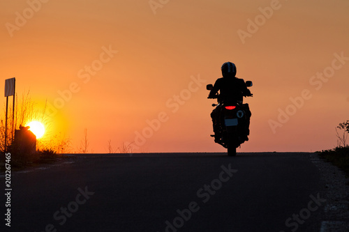 silhouette of rider on a motorbike admiring sunset - space for your text