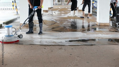 Asian worker cleaning sand wash exterior walkway using polishing machine and chemical or acid