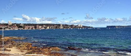 Delwood beach on a sunny day in summer. North Head and South Head are in the background. Sailing boats in Sydney harbour.