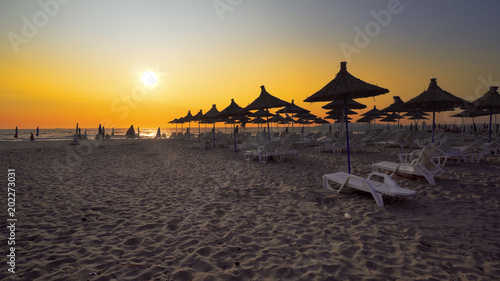 TRAVEL VACATION CONCEPT. Wonderful sunset at the empty beach with loungers and wooden sheds