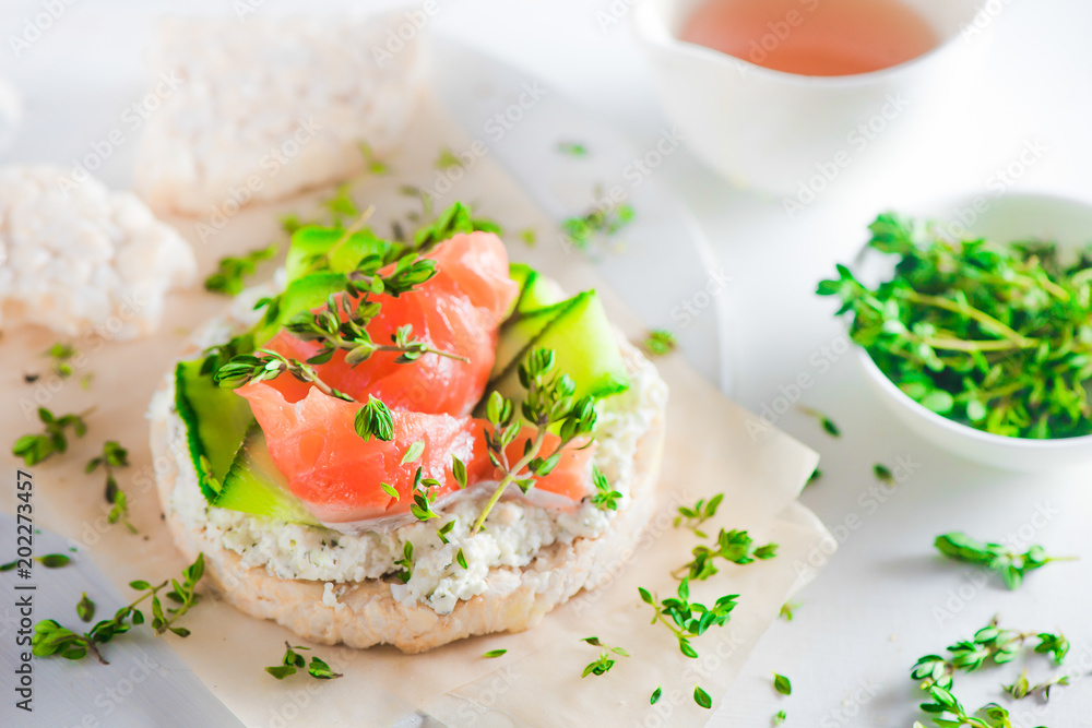 Crisp bread healthy snack with salmon, cottage cheese, cucumber stripes, thyme and pepper. Easy breakfast concept close-up with copy space.