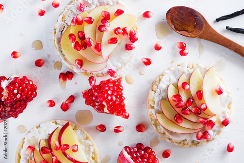 Crisp bread healthy snack with apple slices, soft cottage cheese, vanilla, honey, pomegranate seeds. Easy breakfast concept on a white background with copy space.