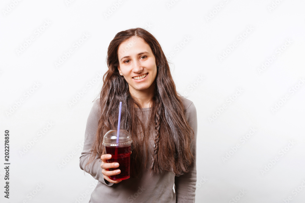Cheerful young woman smiling and holding plastic cup of soda isolated on white Cheerful young woman smiling and holding plastic cup of soda isolated on white