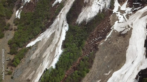 Valbondione, Bergamo, Italy. Spring time. Drone aerial view of remaining snow of the avalanche fall from the mountains peaks in winter photo