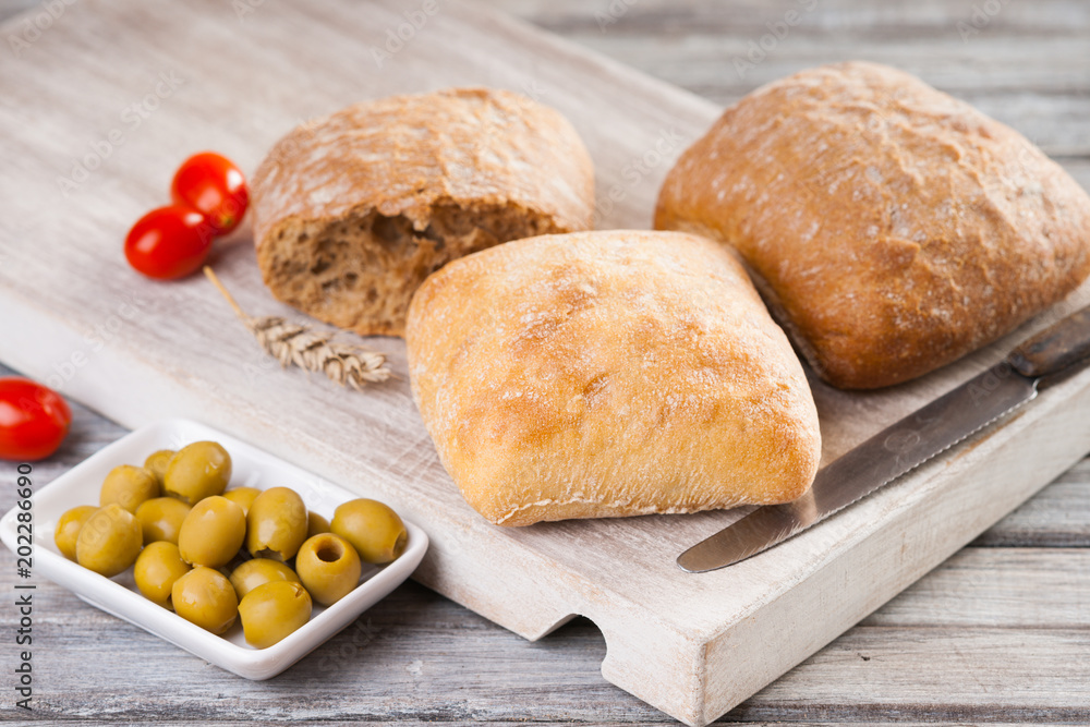 Naklejka premium Homemade bread, tomatoes, olives and knife 