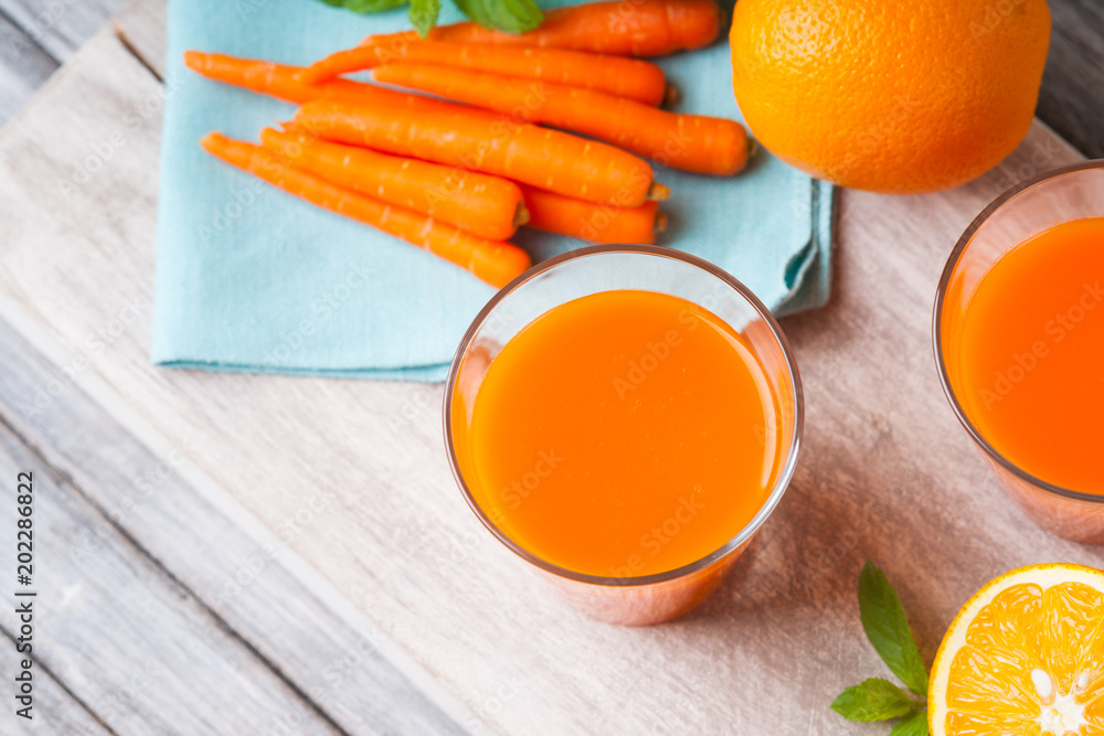 Glasses with carrot juice, mint leaf and sliced orange Glasses with carrot juice, mint leaf and sliced orange