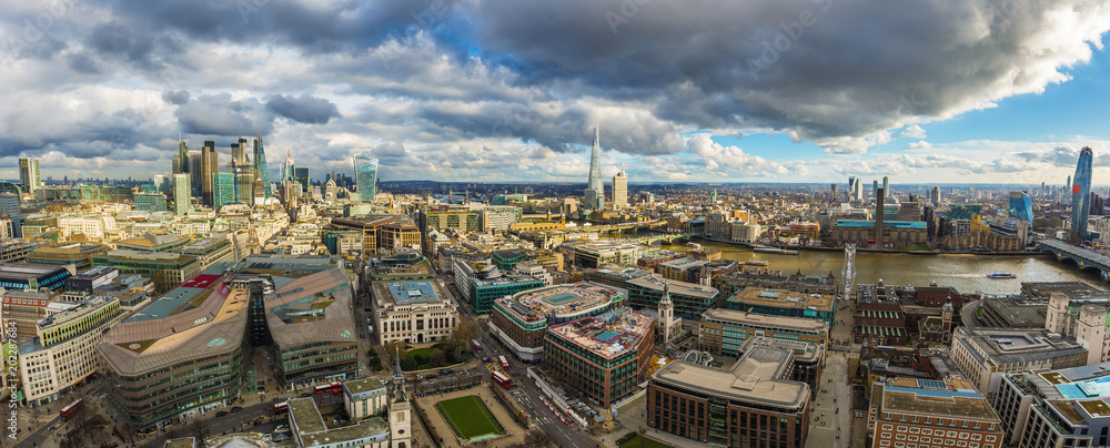 London, England - Panoramic skyline view of London. This view includes the skyscrapers of Bank District, Tower Bridge, Shard skyscraper and Millennium Bridge. Beautiful dramatic clouds and sunshine