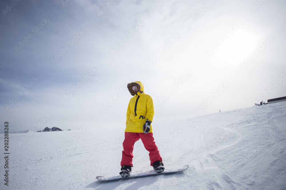 Cool and trendy young professional athlete or amateur snowboard rider  stands on top of hill or