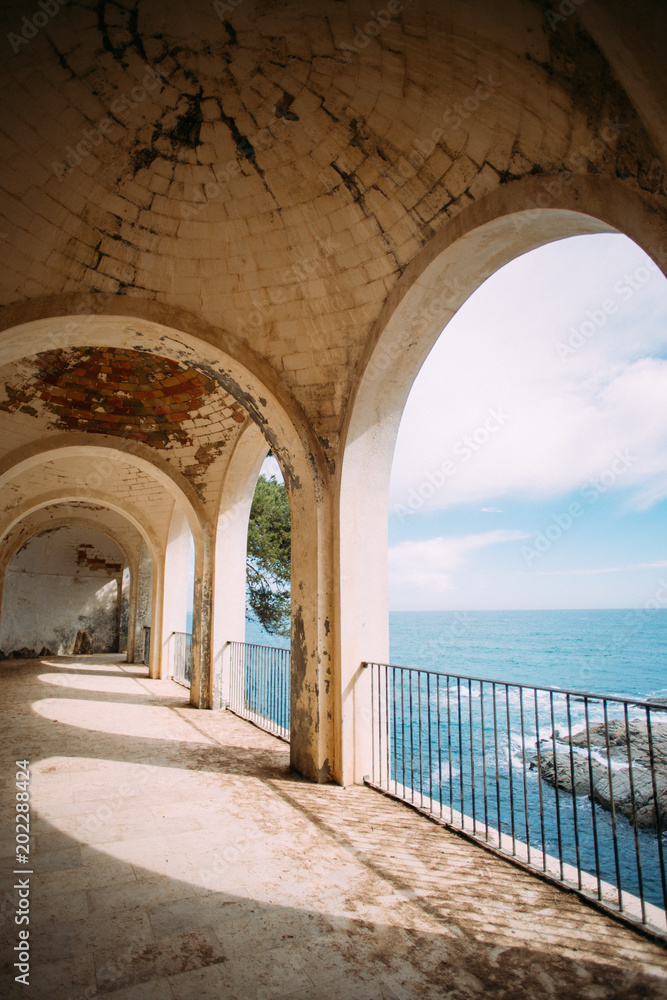 View from ancient building on ocean or sea with roman columns and historic ruins on mediterranean coast line. Beautiful blue sky and waves crush on cliffs. Travel destination for bloggers