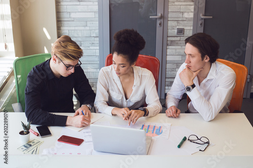 Be focused on the work! Successful smart young team in co-working, sitting in the modern office beside the table and making a decision according to their new project.