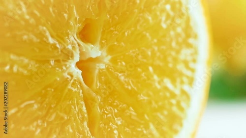 Closeup slow motion footage of juice dripping from orange slice beaing squeezed photo