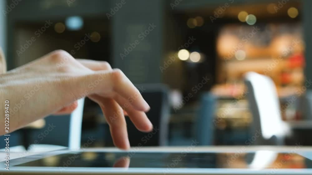 Woman uses tablet pc computer in a cafe shopping center close-up Woman uses tablet pc computer in a cafe shopping center close-up