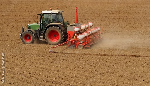 Фотография Tractor with a modern sowing seeds machine in a newly plowed field in springtime