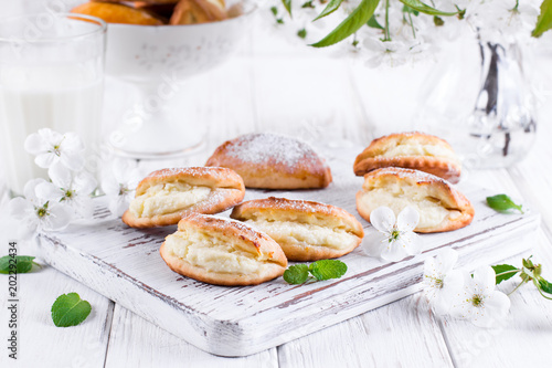 Pasties with cottage cheese and powdered sugar on a light wooden background. Traditional Russian pastry Sochnik.
