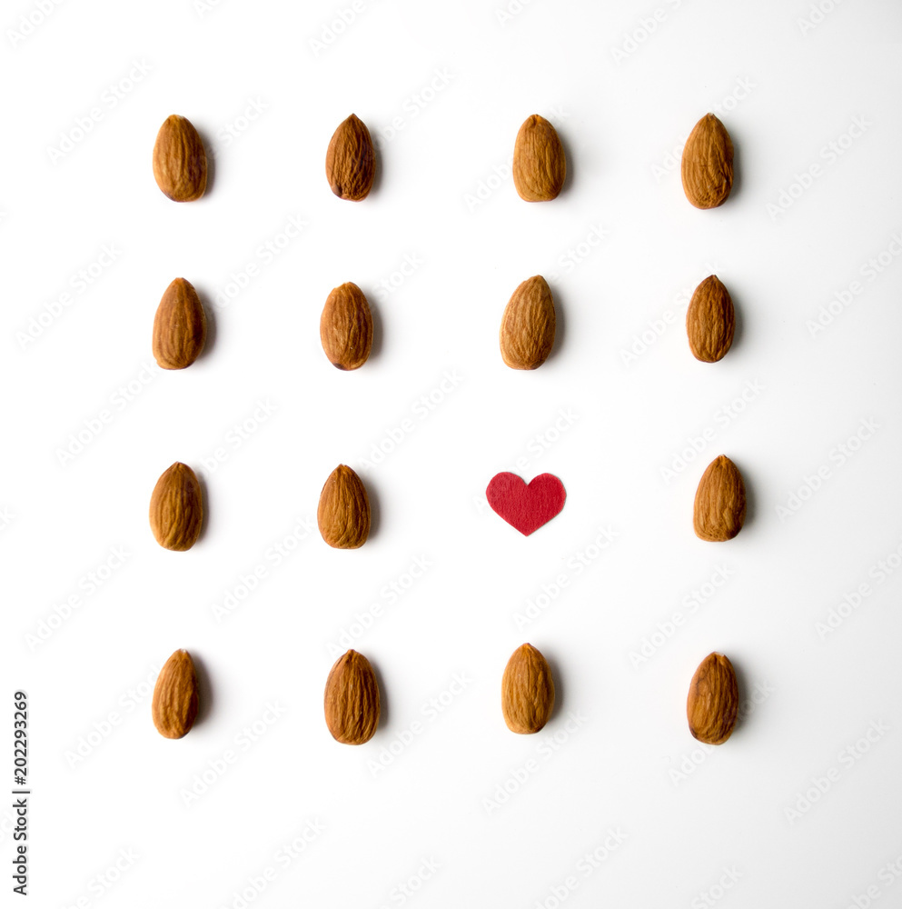 Nuts, almond, tasty and healthy food with lots of vitamins. Almond nuts placed in pattern with red paper heart Nuts, almond, tasty and healthy food with lots of vitamins. Almond nuts placed in pattern with red paper heart