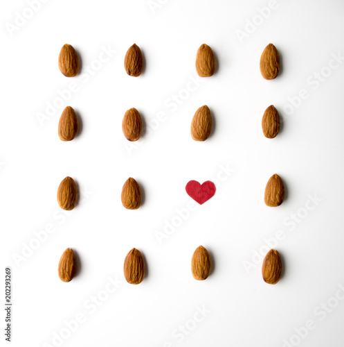 Nuts, almond, tasty and healthy food with lots of vitamins. Almond nuts placed in pattern with red paper heart
