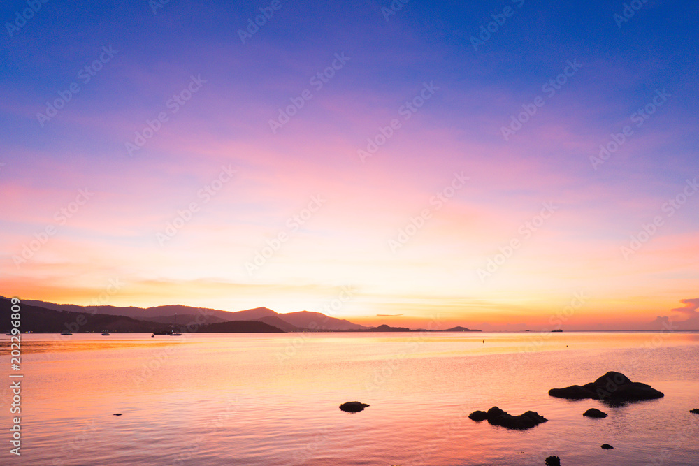 Colorful of dramatic sunset and sunrise with twilight orange sun blazing and blue sky with mountain and calm tropical sea.