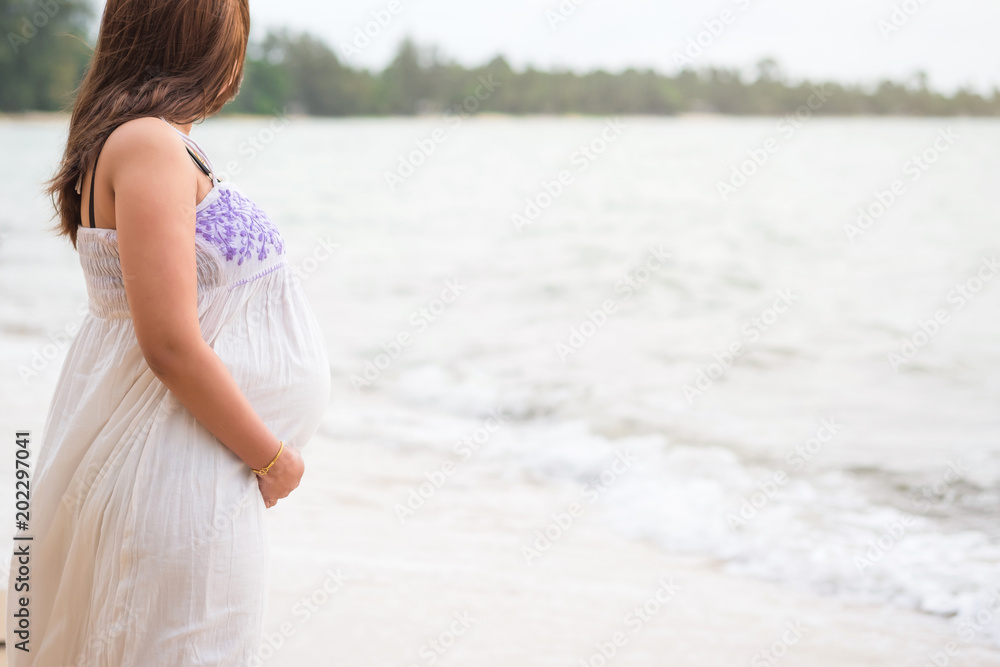 Beautiful pregnant woman standing on tropical beach hand touching on belly. Beautiful pregnant woman standing on tropical beach hand touching on belly.