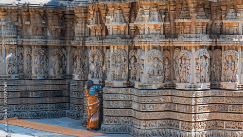 Attendant brushing crevices in intricately carved walls of the 13th century Hindu temple in Somnathpur. It is built of soapstone which is initially optimally soft for carving but hardens over time photo