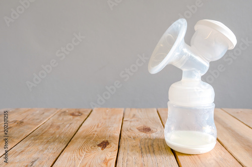 Bottle of automatic pumping breast milk with some mother milk for baby on wooden table with clipping path.