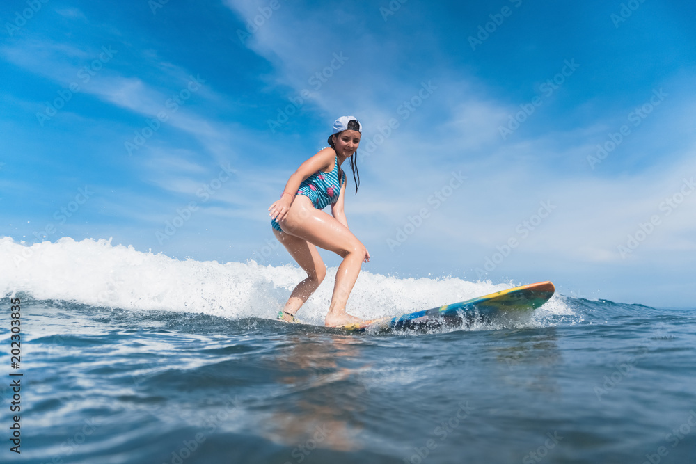 woman in swimming suit and cap surfing in ocean
