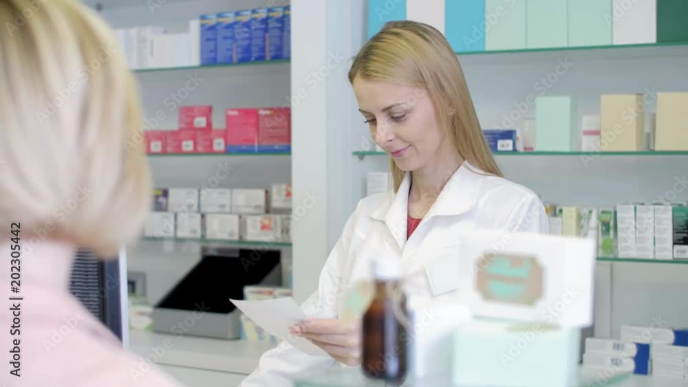 Pharmacist Filling Prescription and Talking to Customer at Pharmacy Counter Pharmacist Filling Prescription and Talking to Customer at Pharmacy Counter