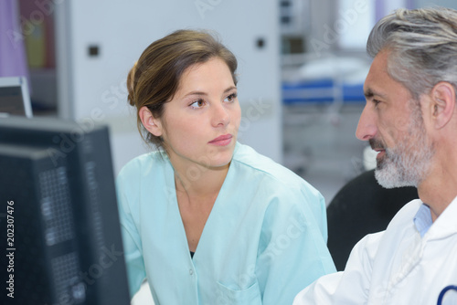 doctor and nurse discussing report oncomputer at the office