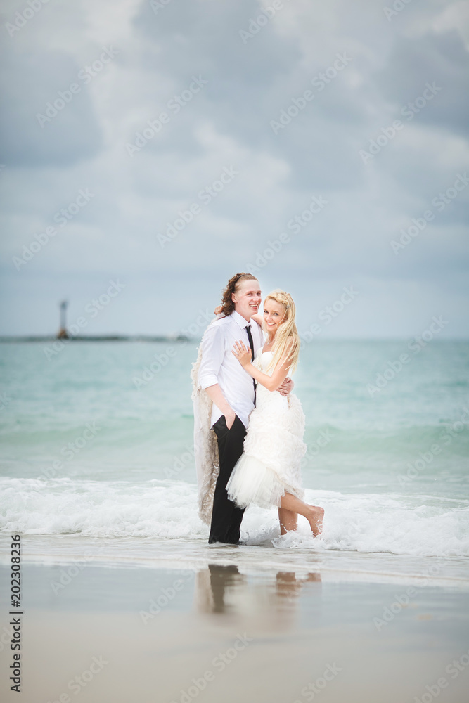 bride in wedding dress and groom hugging at the sea. couple love on deserted beach. bride in wedding dress and groom hugging at the sea. couple love on deserted beach.