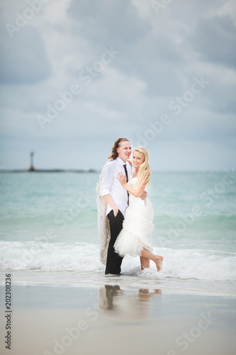 bride in wedding dress and groom hugging at the sea. couple love on deserted beach.