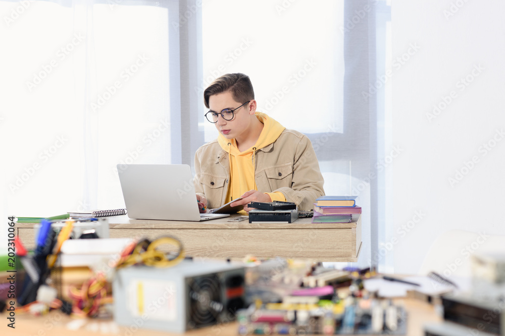 teen boy using laptop and studying at home