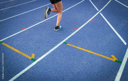 Legs of athlete woman running on racetrack at stadium, copy space