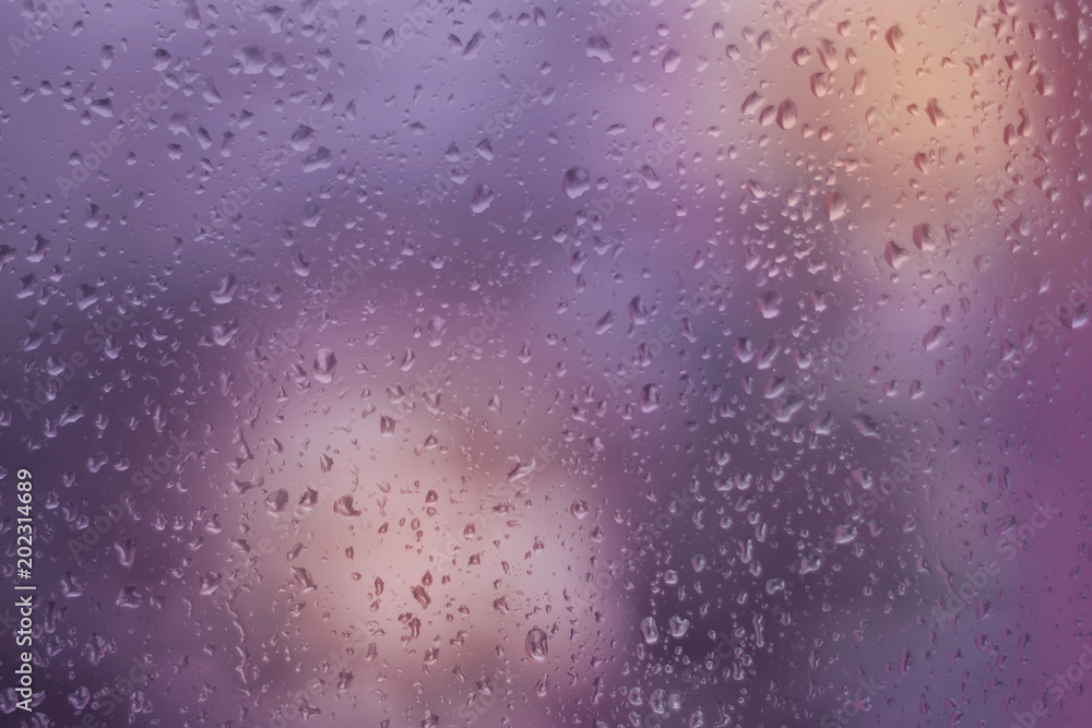 Abstract violet and orange background, texture of rain drops on glass. Raindrops on window, rainy weather.