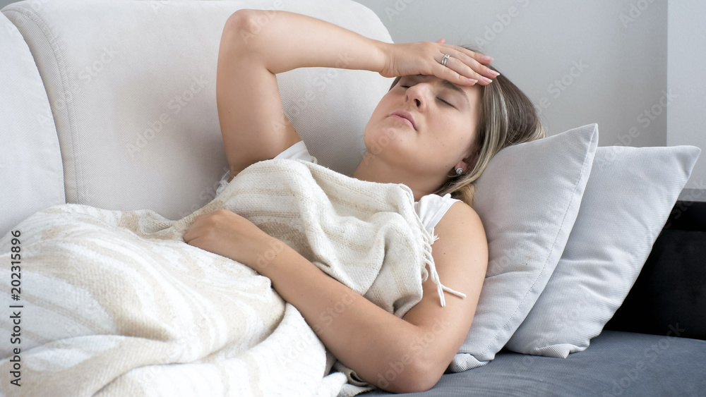 Young woman lying on sofa and suffering from head ache Young woman lying on sofa and suffering from head ache